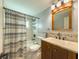 Bathroom featuring stylish wood vanity, tiled shower with patterned curtain, and decorative mirror and lighting at 4725 Soapstone Dr, Tampa, FL 33615