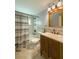 Bathroom featuring stylish wood vanity, tiled shower with patterned curtain, and decorative mirror and lighting at 4725 Soapstone Dr, Tampa, FL 33615
