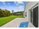A tranquil backyard featuring a patio, green lawn, and screened-in pool in the distance at 630 Lake Cypress Cir, Oldsmar, FL 34677