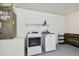 A functional laundry room featuring a modern washer and dryer, and shelving for supplies at 630 Lake Cypress Cir, Oldsmar, FL 34677
