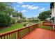 Wood deck with orange rails overlooks a tranquil pond, lush landscaping, and a beautiful blue sky at 6330 99Th N Way # 14B, Seminole, FL 33708
