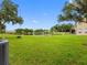 Scenic backyard features pond views, lush green lawn, trees and an AC unit to the side at 6706 47Th N St, Pinellas Park, FL 33781