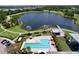 Aerial view of a pool, lounge chairs, and umbrellas with a lake and walking path in the background, offering serene relaxation at 6932 Old Benton Dr, Apollo Beach, FL 33572