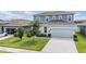 Two-story home features a light-blue facade, a two-car garage, and a well-manicured lawn at 8576 Broadstone Dr, Wesley Chapel, FL 33544