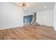 Bright living room featuring wood floors, white walls, modern light fixture, and staircase access at 8576 Broadstone Dr, Wesley Chapel, FL 33544