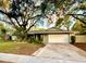 Inviting single-story home featuring a well-kept lawn, mature trees, and a neutral light gray exterior at 939 Woodland Dr, Palm Harbor, FL 34683