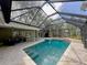 In-ground pool is surrounded by a large screened enclosure and travertine patio at 939 Woodland Dr, Palm Harbor, FL 34683