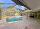 Screened pool area with an in-ground pool surrounded by an expansive travertine patio at 939 Woodland Dr, Palm Harbor, FL 34683