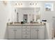 Bathroom with granite countertops and double sinks; decorative mirror, wall art, and door to the toilet room visible at 944 Old Windsor Way, Spring Hill, FL 34609