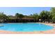 A large community pool is surrounded by mature landscaping and a covered lounge area for residents to enjoy at 944 Old Windsor Way, Spring Hill, FL 34609