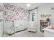 Charming Bedroom featuring a floral accent wall, crib, and comfortable chair at 9608 Greenpointe Dr, Tampa, FL 33626