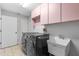 Bright laundry room features modern washer and dryer units plus utility sink and pink overhead cabinets at 10446 Baylor Dr, Spring Hill, FL 34608