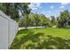 Large backyard featuring lush green grass, mature trees, and a white vinyl fence at 10512 Scenic Hollow Dr, Riverview, FL 33578