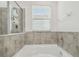 Relaxing tub with tiled surround and bright natural light at 10512 Scenic Hollow Dr, Riverview, FL 33578