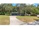 Exterior of a charming single-story home with lush greenery and a long driveway at 12412 Lakeview Dr, Dade City, FL 33525