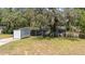 View of the home with mature trees and a portable storage container in the driveway at 12412 Lakeview Dr, Dade City, FL 33525