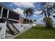 Beautiful waterfront condo with screened porch, palm trees, and grassy area with stairs at 13758 Orange Sunset Dr # 202, Tampa, FL 33618