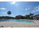 Community pool and lounging area with palm trees, clear blue sky, and well-maintained grounds at 13758 Orange Sunset Dr # 202, Tampa, FL 33618