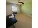 Neutral carpeted room featuring a ceiling fan, window, and dark ottoman seating at 1408 Millstream Ln # 206, Dunedin, FL 34698