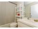 Bright bathroom featuring a toilet, shower with curtain, shelving unit, sink, and mirror at 1535 Nursery Rd # 110, Clearwater, FL 33756