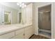 Well-lit bathroom featuring a large mirror, sink, wooden cabinets, and a glass-enclosed shower at 1535 Nursery Rd # 110, Clearwater, FL 33756