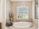 A relaxing bathroom featuring a large soaking tub, decorative window shutters, and a beige tiled surround at 16248 Ivy Lake Dr, Odessa, FL 33556