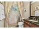 Well-lit bathroom featuring a tiled shower with curtain, vanity with dark countertop, and decorative mirror at 16248 Ivy Lake Dr, Odessa, FL 33556