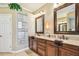 A bathroom featuring dual sinks, a stone accent wall, granite countertops, and dark wood cabinets at 16248 Ivy Lake Dr, Odessa, FL 33556