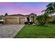Inviting home exterior with a three-car garage, paver driveway, and lush landscaping under a twilight sky at 16248 Ivy Lake Dr, Odessa, FL 33556