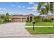 Charming single-story home featuring a three-car garage, brick driveway, and lush landscaping at 16248 Ivy Lake Dr, Odessa, FL 33556