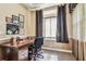 Small office area with a wooden desk, comfortable chair, and natural light streaming through the window at 16248 Ivy Lake Dr, Odessa, FL 33556