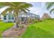Beautiful backyard featuring a well-maintained lawn, lush landscaping, and a screened-in pool area for outdoor enjoyment at 1723 Pacific Dunes Dr, Sun City Center, FL 33573