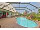 Tranquil screened pool area with lush foliage, water feature, and spacious brick paver patio at 1723 Pacific Dunes Dr, Sun City Center, FL 33573