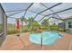 Stunning screened pool area with rock waterfall feature, lush landscaping, and open views at 1723 Pacific Dunes Dr, Sun City Center, FL 33573