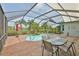 Inviting screened-in pool area with a waterfall feature, dining table, and view of the golf course beyond the enclosure at 1723 Pacific Dunes Dr, Sun City Center, FL 33573