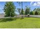 A spacious backyard with lush green grass, play set, fire pit, and a white picket fence at 18596 Rococo Rd, Spring Hill, FL 34610