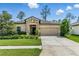 Charming single-story home featuring a stone facade, well-manicured lawn, and a two-car garage at 18596 Rococo Rd, Spring Hill, FL 34610