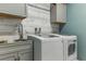 Modern laundry room equipped with high-efficiency washer and dryer and a stainless steel sink at 18596 Rococo Rd, Spring Hill, FL 34610