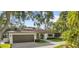 Inviting home featuring a two-car garage, and manicured lawn with lush surrounding trees at 208 Live Oak Ln, Largo, FL 33770