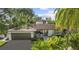 Charming home showcasing lush landscaping, a gray roof, and an attached two-car garage at 208 Live Oak Ln, Largo, FL 33770