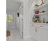 Hallway with white cabinetry and shelving, tiled floors, and natural light streaming in from a nearby window at 208 Live Oak Ln, Largo, FL 33770