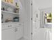Bright hallway with white cabinetry and shelving, tiled floors, and glass doors leading to an outdoor patio at 208 Live Oak Ln, Largo, FL 33770