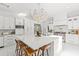Bright and airy white kitchen featuring a large island with seating, stainless steel appliances, and modern lighting at 208 Live Oak Ln, Largo, FL 33770