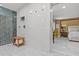 Glass enclosed shower with wood bench and marble wall with shower shelf, view to bedroom at 208 Live Oak Ln, Largo, FL 33770
