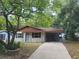 Single-story home featuring a carport, mature trees, and a well-maintained front yard at 21352 Lehouier Dr, Brooksville, FL 34601