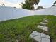 A view of the grassy backyard with white privacy fence and stepping stones at 2328 W La Salle St, Tampa, FL 33607