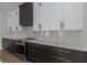 A modern kitchen with white cabinets, a gray countertop, stainless steel appliances, and a tiled backsplash at 2328 W La Salle St, Tampa, FL 33607
