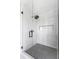 Elegant glass shower stall with gray and white marble-patterned walls and geometric floor tiles at 2328 W La Salle St, Tampa, FL 33607