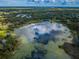 Expansive aerial view showcases a serene lake surrounded by lush greenery, reflecting the cloudy sky above at 2459 Parkstream Ave, Clearwater, FL 33759