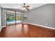 This bedroom features hardwood floors, a ceiling fan, and sliding glass doors that lead to the pool at 2459 Parkstream Ave, Clearwater, FL 33759